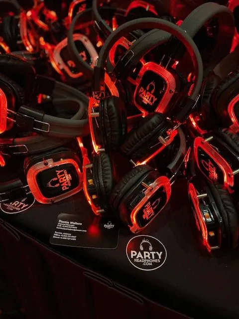 A close-up of high-quality wireless silent disco headphones showing the glowing LED indicators used for different audio channels.