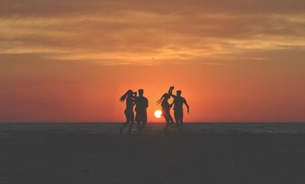 four people dancing at sunset